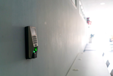 A close-up image of a fingerprint scanner mounted on a wall in an office. This device enhances...