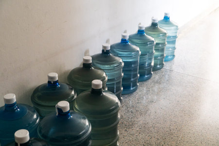 A series of clear water jugs lined up in a bright corridor, showcasing an organized and refreshing...