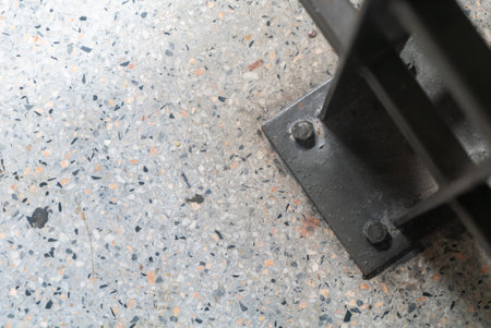 A close-up view of a sturdy metal frame resting on a textured floor surface, showcasing industrial...