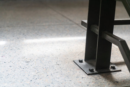 A close-up view of a metal support structure resting on a concrete floor. The image captures the...