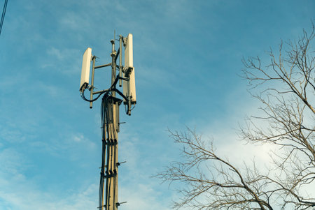 A cell tower rises against a bright blue sky, enhancing telecommunications. This image captures both...