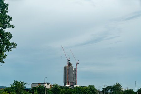 A construction site bustling with activity, featuring cranes and workers, set against a moody gray sky. This image captures urban development in progress.の写真素材