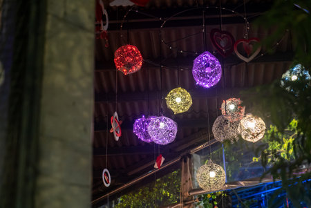 Beautiful colorful hanging lights create a cozy ambiance in a cafe setting. The intricate design and...