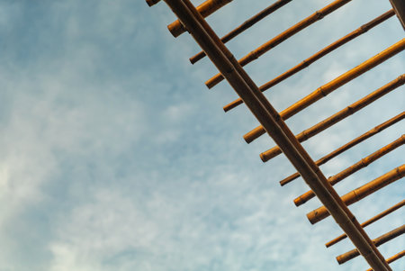 A unique bamboo structure framed against a serene blue sky. The natural design enhances the tranquil atmosphere, showcasing wood textures and artistic lines.の写真素材