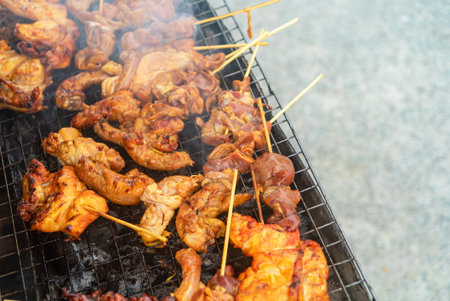 A mouthwatering display of various grilled meat skewers sizzling on a barbecue grill, surrounded by...