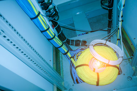 A detailed view of colorful Ethernet cables neatly organized in a wiring closet, showcasing yellow...