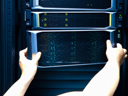 A technician's hands carefully place a server into a rack in a data center. This image illustrates...