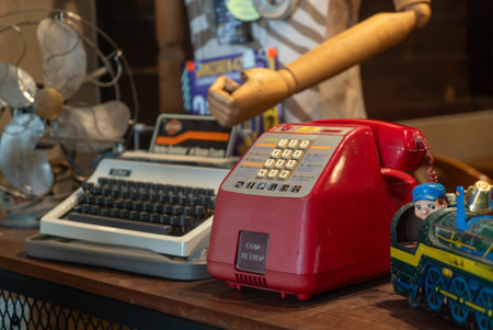 A captivating arrangement of vintage desk items including a typewriter, red telephone, and...