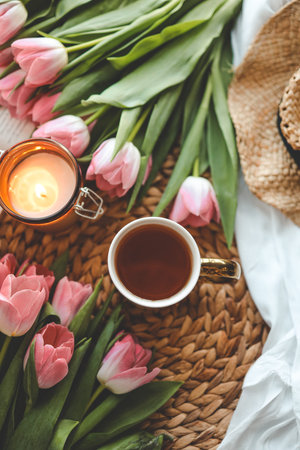 Beautiful spring composition, a cup of tea, tulips, a candle and a hat.