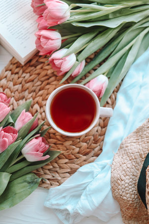 A cup of tea with tulips on rose background