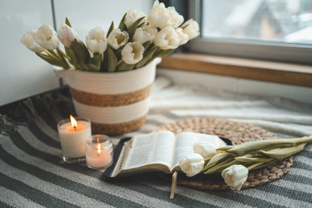 Open Bible with flowers and candles in a cozy home interior. Christian beautiful morning...