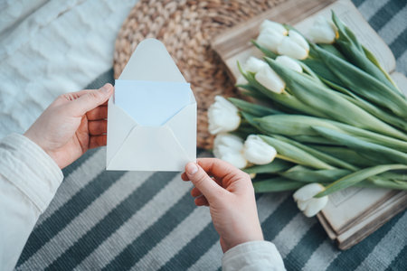 Hands with an empty envelope on a background of flowers, a place for your text.