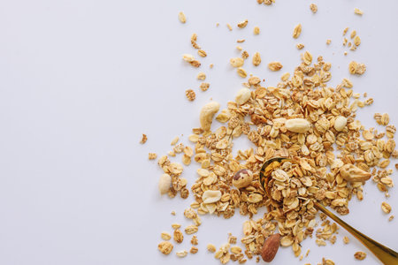 Granola on spoon isolated on white background, copy space. Healthy snack or breakfast concept -...