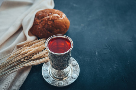 Bread, wine and ears of wheat on a dark background.