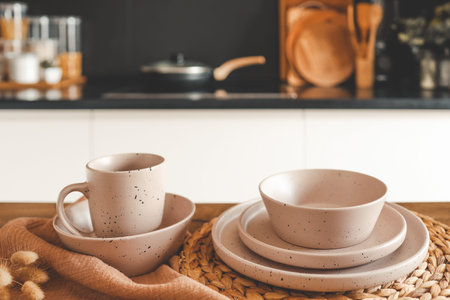 Set of beige minimalist dishes on a table against the backdrop of a kitchen.