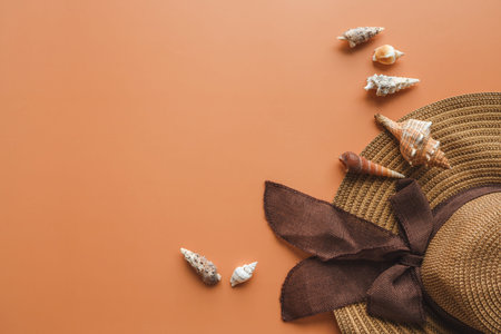 Beautiful straw hat and seashells on color background, top view.