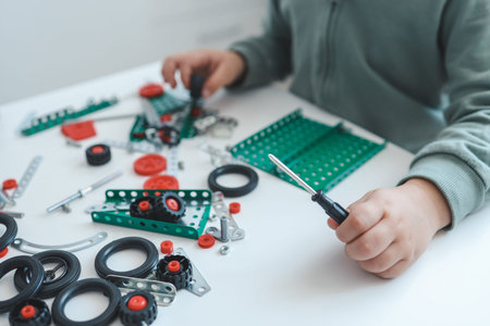 A little boy with a screwdriver in his hands plays with a metal constructor.の写真素材