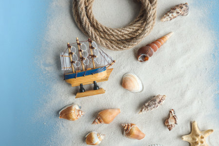 Marine summer composition. Shells, ship, rope on a blue background.