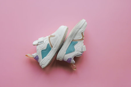 White children's sneakers on a pink background with copy space. Banner.の写真素材