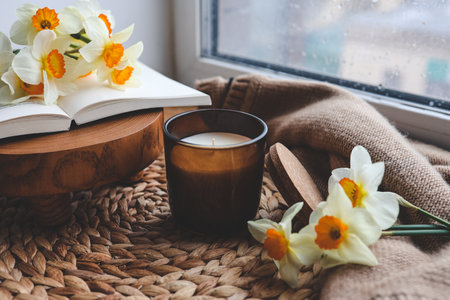 Candle and daffodils on the windowsill, spring composition.の写真素材