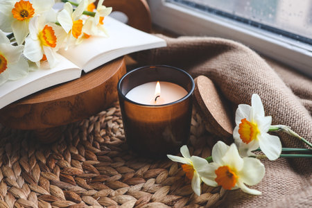 Candle and daffodils on the windowsill, spring composition.の写真素材