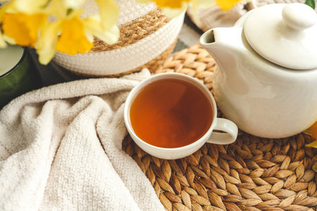 Cup of tea, candles, basket with daffodils, spring aesthetic photo.の写真素材