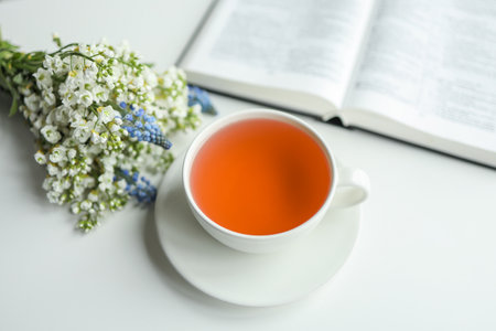 Open book with flowers and a cup of tea on a white background.の写真素材