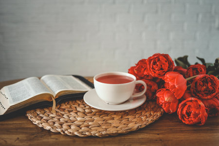 Open bible with a cup of tea on light wood.の写真素材
