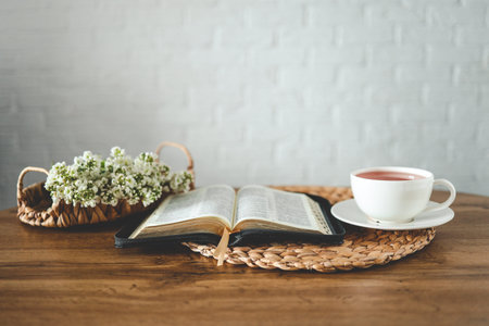 Open bible, flowers and a cup of tea, space for text.