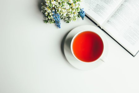 Open book with flowers and a cup of tea on a white background.