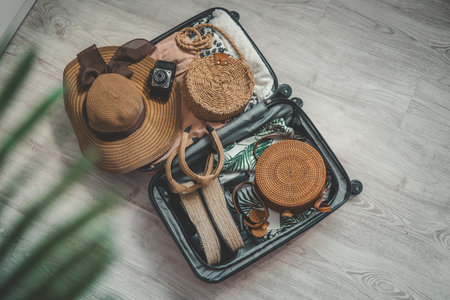 Suitcase, hat, bag and sunglasses on wooden floor.