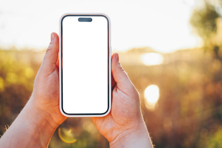 Phone in hands with isolated screen at sunset.