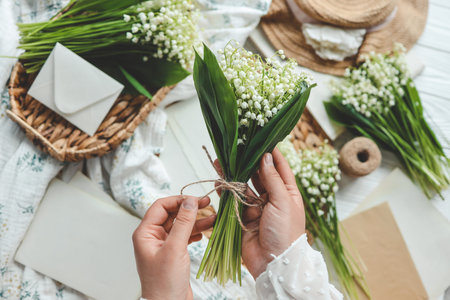 Girl florist holds a bouquet of lilies of the valley in her hands.