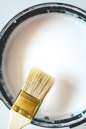 Paint brush resting on paint tin viewed from above.