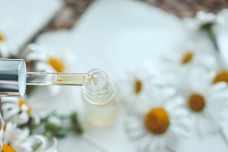 Composition with chamomile flowers and cosmetic bottle of essential oil on white background, top view.の写真素材