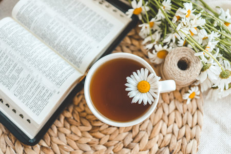 Open Bible and daisies on the windowsill, summer composition.