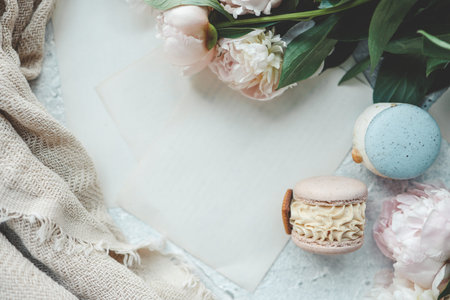 Greeting card with place for your text, white peonies and sweet macarons top view.