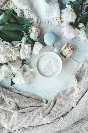 Cup of coffee, sweet macaroons and white peonies, beautiful aesthetic photo.