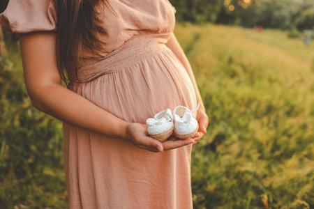 A pregnant woman holds cute baby shoes in her hands, the concept of expecting a baby.