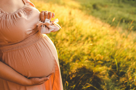 A pregnant woman holds cute baby shoes in her hands, the concept of expecting a baby.