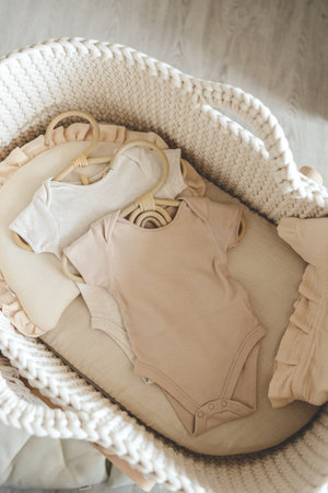 Two neutral bodysuits in a baby cradle, baby clothes.