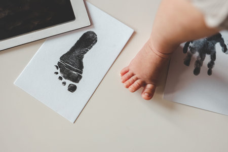 Baby footprints on white paper. Black footprint. The process of creating a baby footprint.