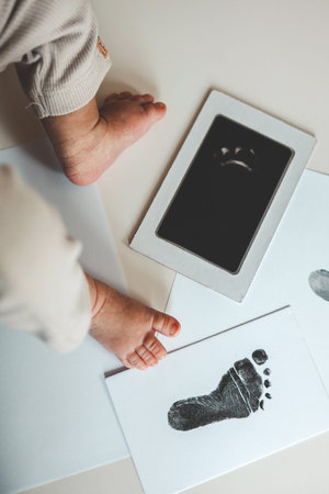 Baby footprints on white paper. Black footprint. The process of creating a baby footprint.