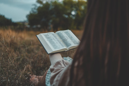 Girl with a Bible in her hands in nature, evening prayer and worship.