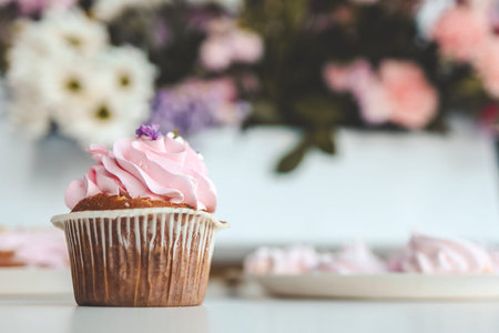 Pink sweet cupcake close-up on a background of flowers.