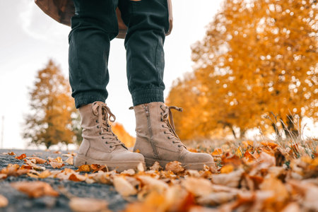 A man walks along an autumn road, boots close-up.