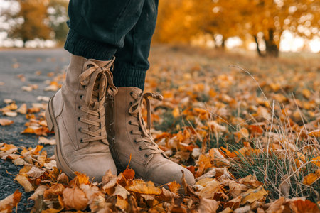 A man walks along an autumn road, boots close-up.
