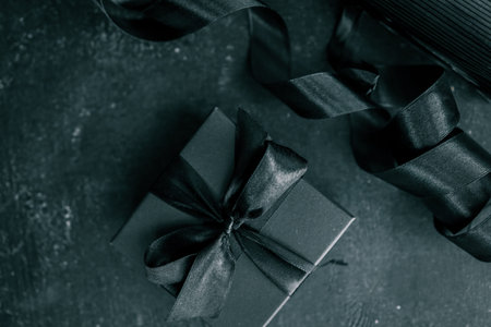 Black Friday sale concept. Gift box with black ribbon isolated against black background, top view