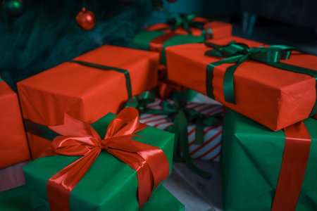 Christmas gifts red and green with bow near Christmas tree.