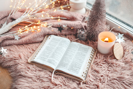 Open Bible in cozy pink winter home morning atmosphere.